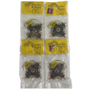 Może przedstawiać: Kilka metalowych ramek Florentine Styled w przezroczystych plastikowych opakowaniach. Ramki mają złote obramowanie i ciemny, teksturowany środek. Każde opakowanie zawiera żółtą etykietę z napisem "Florentine Styled".