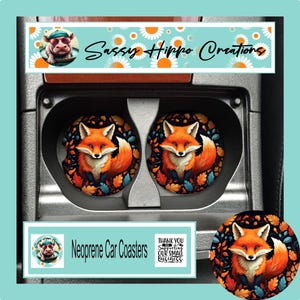 May include: Two circular neoprene car coasters featuring a vibrant orange fox illustration surrounded by colorful autumn leaves. The coasters are placed inside a vehicle cup holder. The image includes text reading Sassy Hippo Creations and Neoprene Car Coasters.