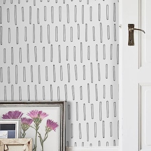 Puede incluir: Una pared blanca con un papel tapiz de patrón geométrico en blanco y negro. El papel tapiz presenta un patrón repetitivo de líneas finas verticales. La pared está decorada con tres cuadros enmarcados y una puerta. El texto "Buy on patternsColoray Etsy Shop" es visible en la esquina inferior derecha de la imagen.