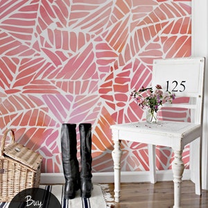 Puede incluir: Una silla blanca con el número "125" en el respaldo se encuentra frente a una pared cubierta con un papel tapiz de patrón de hojas geométricas rosa y naranja. El papel tapiz tiene un efecto acuarela. Dos botas de cuero negras están sobre una alfombra rayada frente a la silla. El texto "Buy on patternsColoray Etsy Shop" está en un círculo negro en la esquina inferior izquierda de la imagen.
