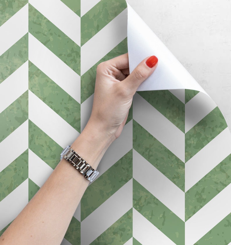 May include: A roll of green and white chevron patterned wallpaper being peeled back to reveal the adhesive backing.