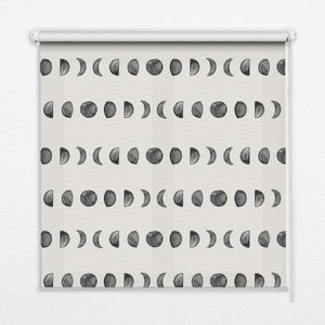 May include: A white roller shade with a repeating pattern of black watercolor moon phases. The moon phases include a full moon, crescent moon, half moon, and new moon.