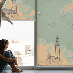 以下が含まれることがあります： 建物が見える窓際に座っている若い人。窓には、灯台と航海図のデザインが描かれた薄い青とベージュの模様のブラインドがかけられています。