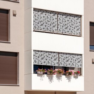 May include: A modern apartment building with brown window shutters and white patterned window shades. The building has a balcony with potted plants.