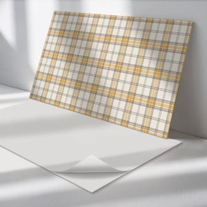May include: A white sheet of paper with a yellow and gray plaid pattern printed on it. The paper is folded over on itself, revealing the white underside.