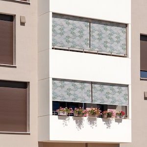 May include: A building with multiple windows featuring brown roller shades and patterned white and green window coverings. The windows are on a balcony with potted plants.