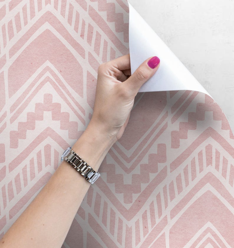 May include: Pink and white geometric patterned wallpaper with a hand peeling back a corner to reveal the white backing.