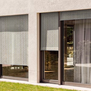 May include: Two large windows with white patterned blinds. The windows are framed in dark brown and have a view of a green lawn.