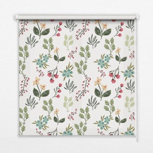 以下が含まれることがあります： 白いローラーシェードに、青、黄、緑、ピンクの花が描かれた花柄。