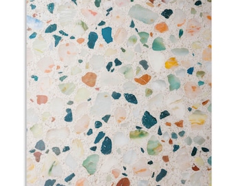 May include: A close-up of a terrazzo floor with a white background and colorful chips of blue, green, orange, and brown.