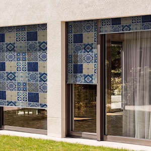 May include: Two windows with white frames and blue and beige patterned blinds. The blinds are made of fabric and have a geometric design. The windows are closed and the blinds are pulled down.