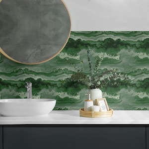 Könnte beinhalten: Ein Badezimmer-Waschtisch mit einem weißen Waschbecken und einer grünen Marmor-Rückwand. Über dem Waschbecken befindet sich ein runder Spiegel und auf der Ablage ein kleines Tablett mit einer Seifenflasche und einem Bilderrahmen.