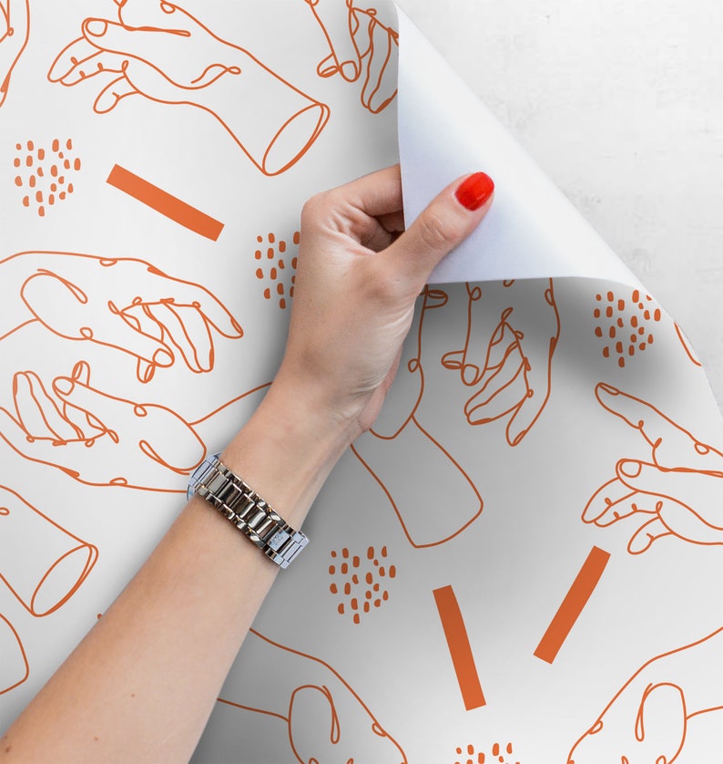Pu&ograve; includere: Carta da regalo bianca con un motivo ripetitivo di disegni di mani arancioni e forme astratte. Una mano sta staccando la carta per rivelare pi&ugrave; del motivo.