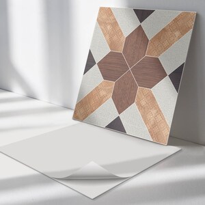 May include: A peel-and-stick tile sticker with a geometric pattern featuring brown, beige, and gray colors. The sticker is designed to look like wood and has a white backing.