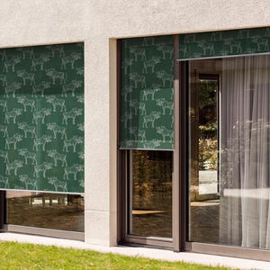 May include: Two windows with green patterned roller shades. The shades have a white outline of a moose repeated across the fabric. The windows are in a modern home with white walls.