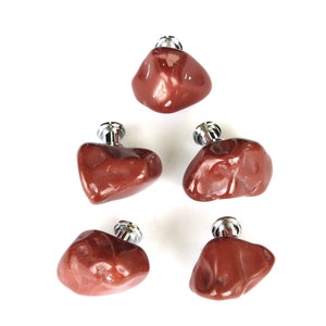 May include: Five polished, reddish-brown stone pendants with silver-colored metal caps. The stones have irregular shapes and a glossy finish, arranged against a white background. These pendants are suitable for jewelry making.