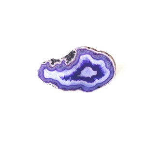 May include: A purple agate slice with a white center and concentric bands of purple and white.