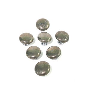 May include: Seven round, metallic cabinet knobs with a mottled, greenish-gray finish. Each knob has a short, silver-colored stem. The knobs are arranged in a circular pattern against a white background.