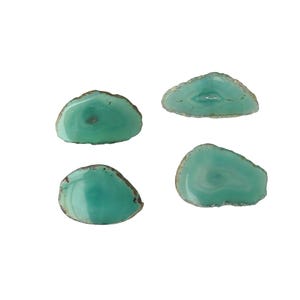May include: Four polished, teal-colored agate slices with brown edges are displayed against a white background. The translucent stones have a natural, organic shape, showcasing the unique patterns and variations within each piece.