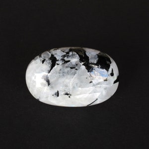 May include: A white and black moonstone tumbled stone with a smooth, oval shape.
