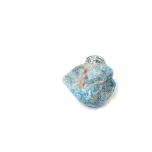 May include: A blue and brown rock with a silver metal top. The rock is rough and textured.