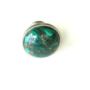 May include: A round green and gold malachite knob with a silver metal base.