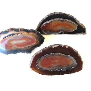 May include: Three agate slices with brown and black outer edges and red and white inner bands.