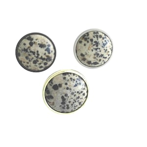 May include: Three circular buttons featuring a speckled dalmatian-like pattern in cream, gray, and black. Each button has a distinct metallic rim, with one in a dark bronze tone, one in a silver tone, and one in a gold tone finish.