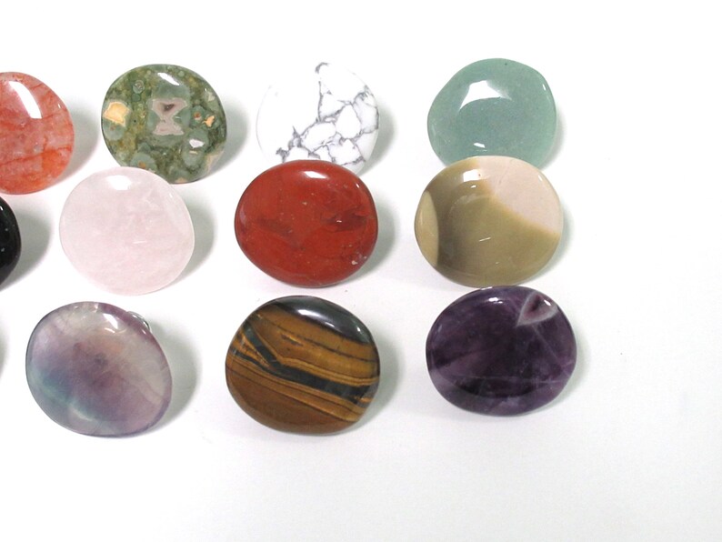 K&ouml;nnte beinhalten: Sortiment von 12 glatten, runden, polierten Steinen in verschiedenen Farben und Mustern. Die Steine sind in einem Kreis auf wei&szlig;em Hintergrund angeordnet.
