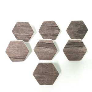 May include: Seven hexagonal wooden coasters with a brown woodgrain pattern. The coasters are arranged in a staggered pattern on a white surface.