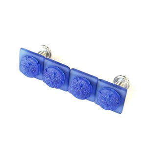May include: Four blue glass cabinet knobs with a sand dollar design. Each knob has a silver metal base.