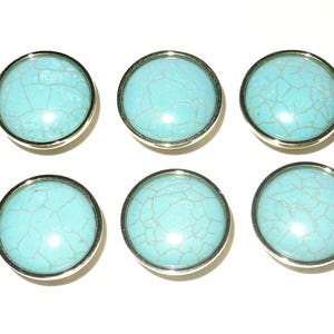 May include: Six round turquoise cabinet knobs with silver-colored rims. The turquoise has a cracked, web-like pattern. The knobs are arranged in two rows of three against a white background.
