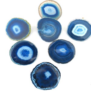 May include: Seven blue agate slices with different patterns and shades of blue. The agate slices are round and have a polished finish.