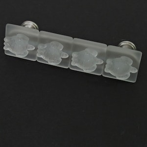 May include: Four frosted glass cabinet knobs with a silver finish. Each knob features a raised design of a sea turtle.