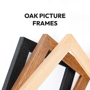 Op de afbeelding: Drie houten fotolijsten in een stapel, met verschillende afwerkingen in zwart, middenbruin en licht natuurlijk eikenhout. De tekst OAK PICTURE FRAMES staat in dikke zwarte hoofdletters boven de lijsten op een witte achtergrond.