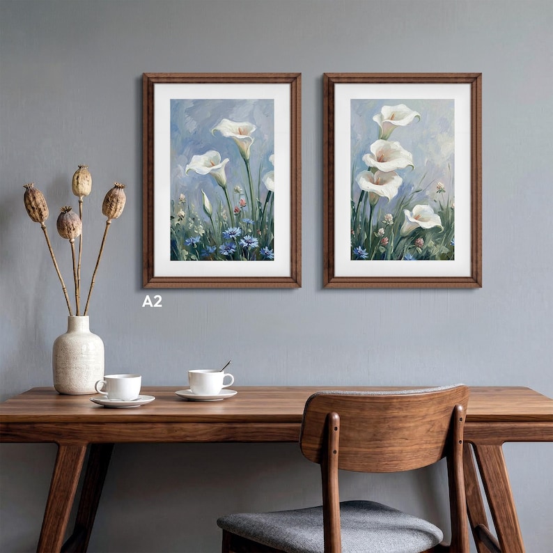 Set of two A2 wood frames hanging side-by-side on a gray wall above a wooden desk. Each solid birch wood picture frame features custom white matting displaying elegant floral artwork. A perfect hanging photo frame solution for creating a stylish gallery wall or elevating your home office and living room decor.