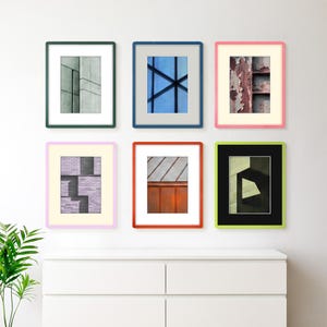 May include: A gallery wall arrangement of six rectangular framed prints featuring abstract architectural photography. The frames are colored dark green, blue, pink, light purple, orange, and lime green, each containing a white or black mat board.