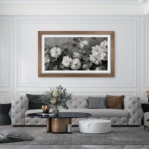 big open fancy living room with a big couch and marble surfaces, shiny copper metallic details with big white wall with moldings, walnut wood frame tv on the wall, contemporary black and white flower painting