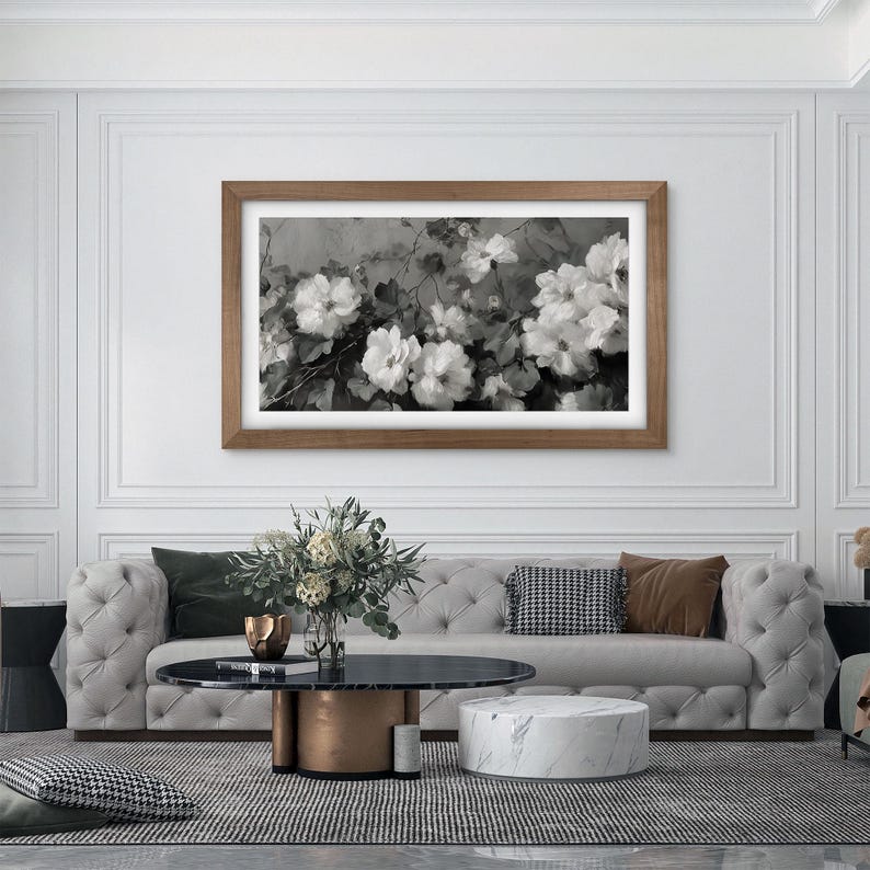 big open fancy living room with a big couch and marble surfaces, shiny copper metallic details with big white wall with moldings, walnut wood frame tv on the wall, contemporary black and white flower painting