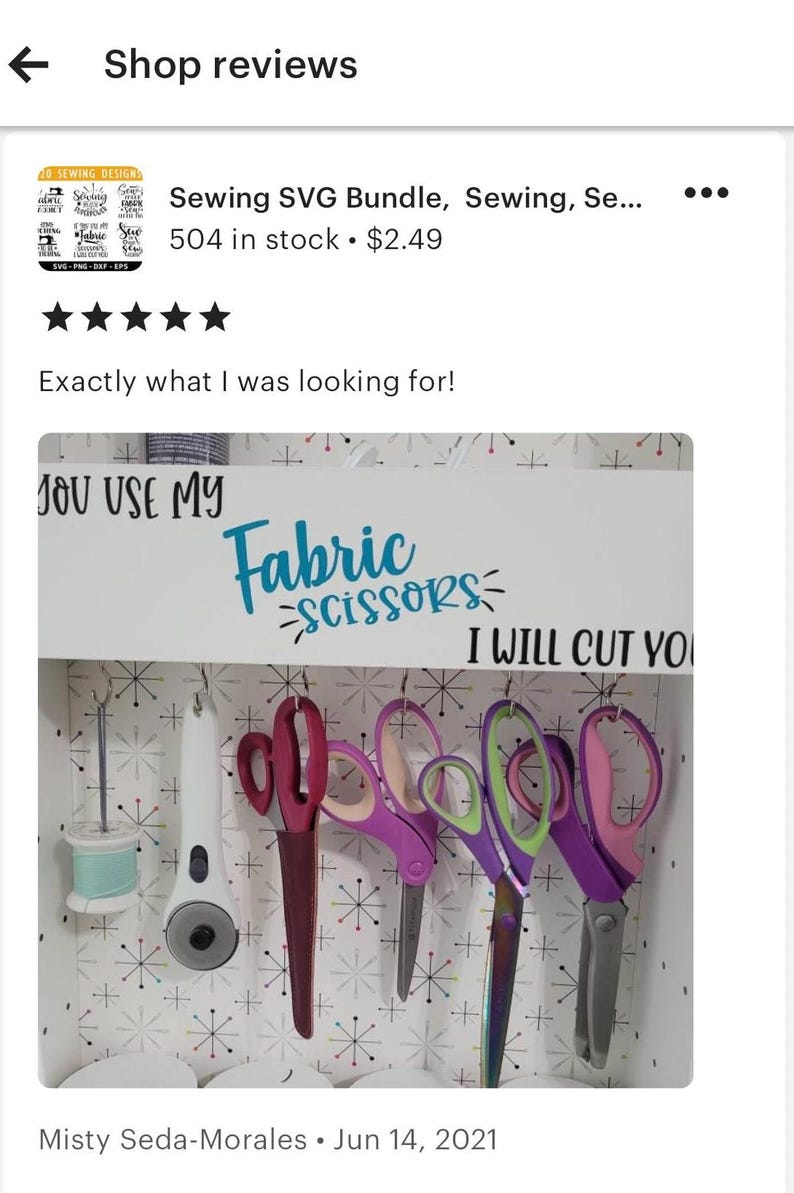 以下が含まれることがあります： 白い木製の看板に「You Use My Fabric Scissors I Will Cut You」という文字が青と黒で書かれています。看板は白と黒の星柄の壁に掛けられています。看板には5組のハサミがフックに掛けられています。