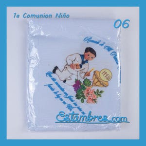 May include: A white fabric item wrapped in clear plastic featuring a printed illustration of a child in a sailor suit kneeling before a golden chalice with the text 1a Comunion Niño 06, Recuerdo de Mi Primera, and Estambres.com.