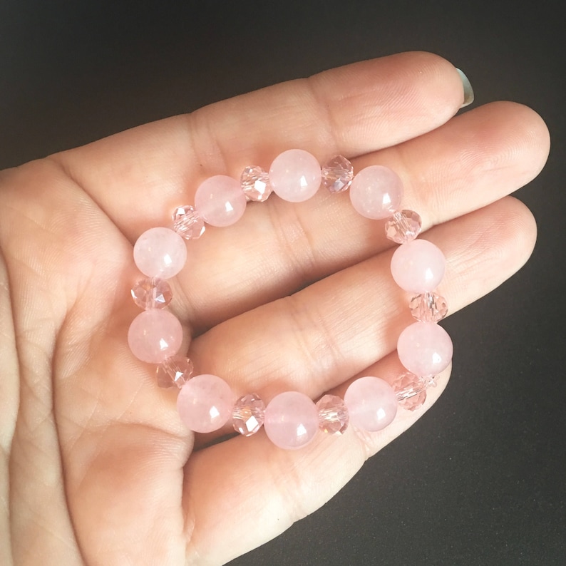 May include: A pink and clear crystal bracelet with round beads. The bracelet is made with rose quartz and crystal beads.