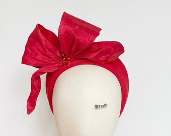 May include: A bright pink headband with a large bow and jeweled embellishments.