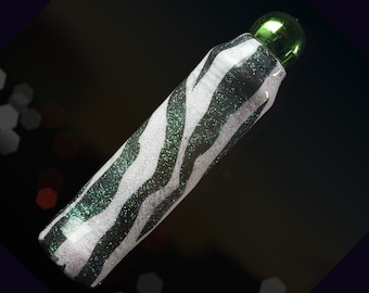 May include: A black and white zebra patterned bottle with a green glitter finish and a green plastic cap.