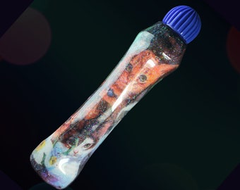 May include: A clear plastic bottle with a blue cap filled with glitter and a colorful image of a cat inside.