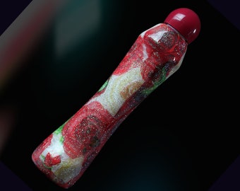 May include: A decorative bottle with a red cap and a floral design. The bottle features a pattern of red roses, green leaves, and silver glitter on a white background. The bottle is elongated and has a rounded top.