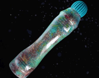 May include: A teal glitter glue bottle with a teal cap. The bottle is filled with iridescent glitter and has a clear, translucent body.