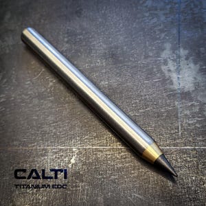 May include: A metallic gray pencil with a gold-colored tip and a black graphite point. The pencil is cylindrical and has the text "CALTI TITANIUM EDC" printed on the surface.
