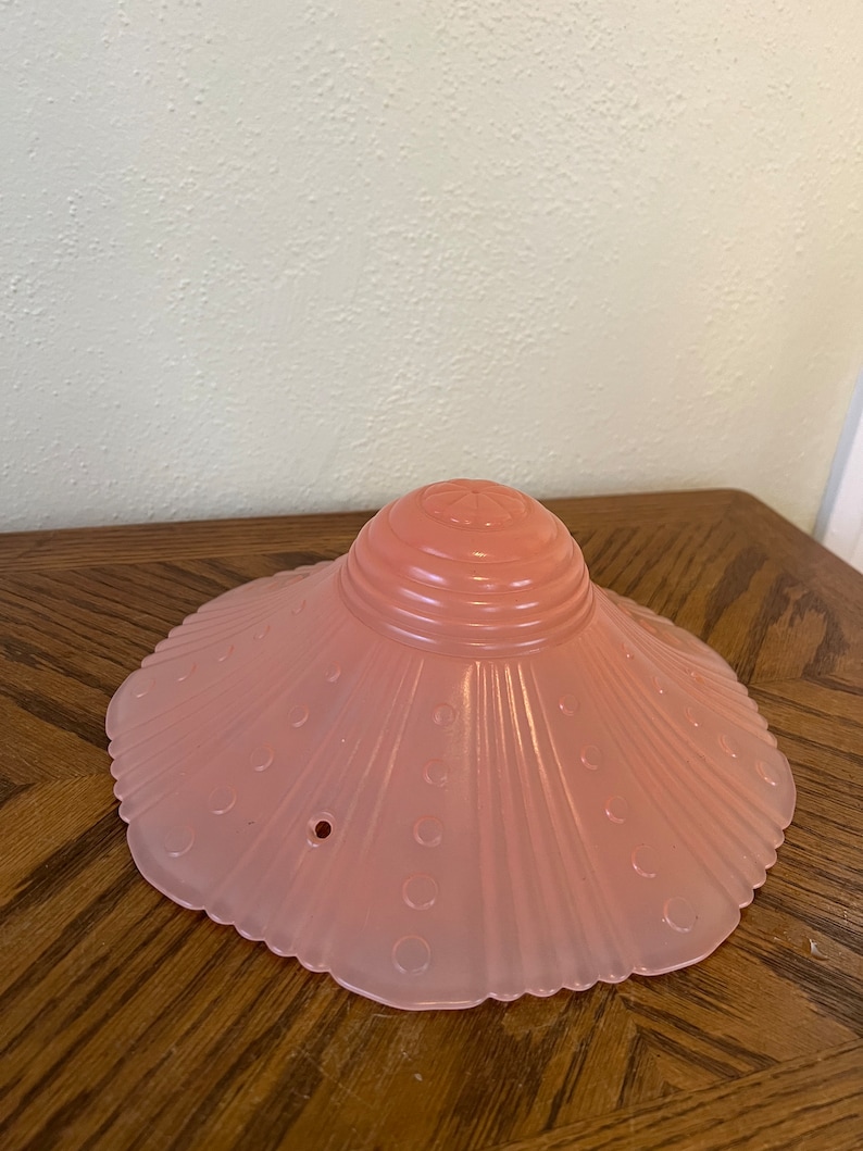 Peut inclure: Un abat-jour de lampe en verre rose avec un bord festonn&eacute; et une surface textur&eacute;e. L'abat-jour a un petit trou au centre.