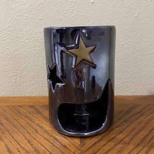 Może przedstawiać: Ceramiczny palnik do olejków w ciemnoniebieskim kolorze z motywem złotej gwiazdy. Palnik ma wycięcie na świeczkę typu tealight.